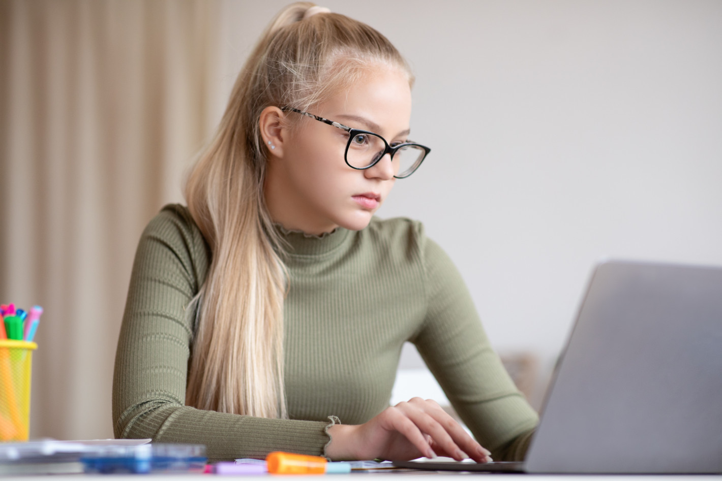 Konzentriertes Mädchen macht Hausaufgaben am Laptop